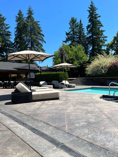 Outdoor pool area featuring RM sun Unbrella (stripe) 8x8, providing shade for loungers under clear blue sky.