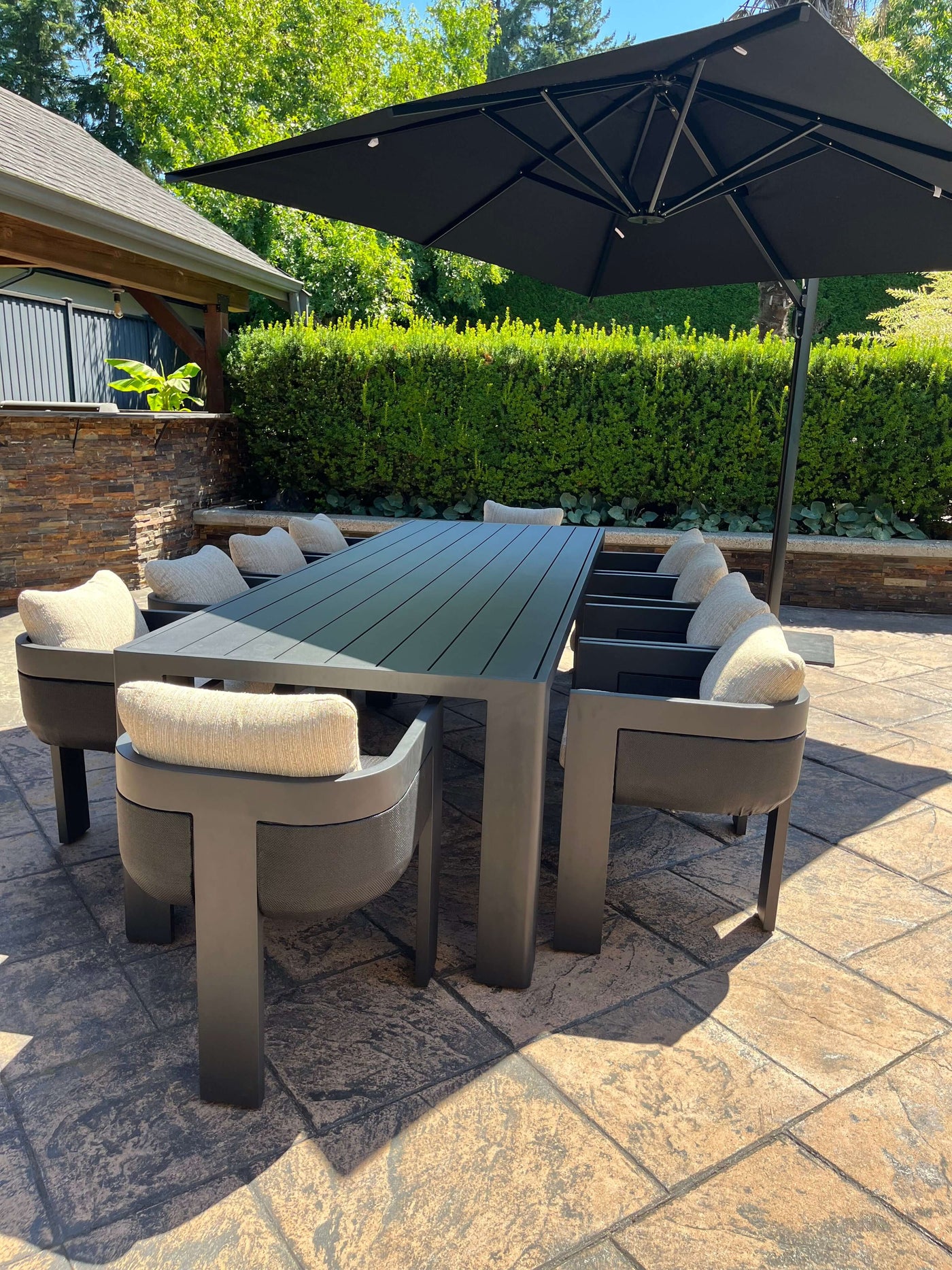 Stylish aluminum outdoor dining set with cushioned chairs under a large umbrella, perfect for outdoor gatherings.