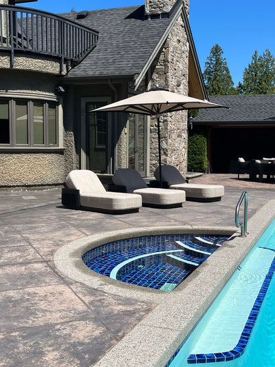 RM Sun Umbrella (stripe) 8x8 providing shade over lounge chairs by the poolside in a sunny backyard.