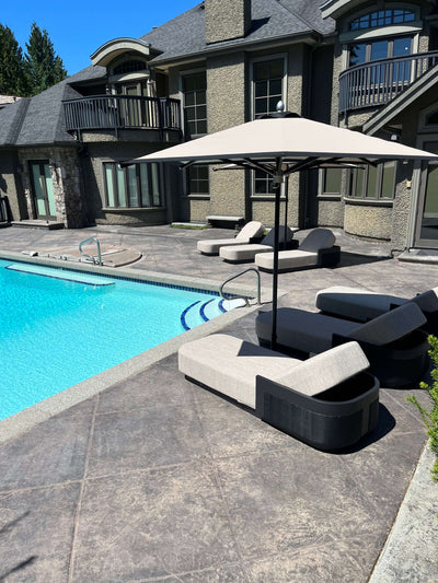 RM Sun Unbrella (stripe) 8x8 providing shade over poolside lounge chairs near a swimming pool.