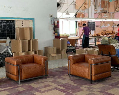 Two LC3 arm chairs in leather upholstery set in a workshop, showcasing a classic mid-century modern design.