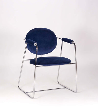 Mera chair featuring a sleek chrome frame and plush navy upholstered seat and arms, perfect for stylish dining spaces.
